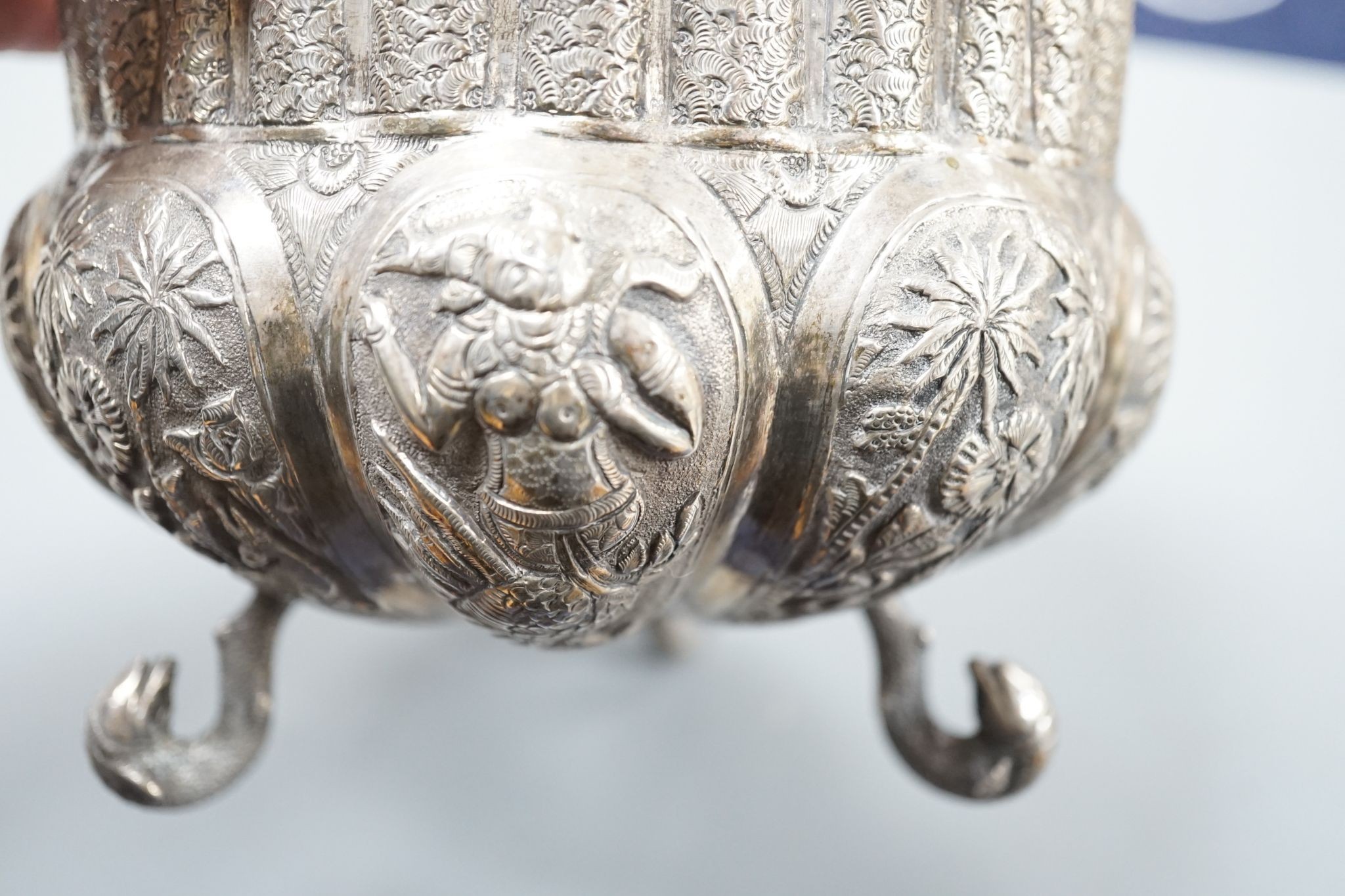 An Indian embossed white metal bowl, on three dolphin feet, diameter 13cm, 10oz.